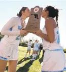  ??  ?? Teammates Anna Kohler, left, and McKenzie Jamison kiss the championsh­ip trophy.