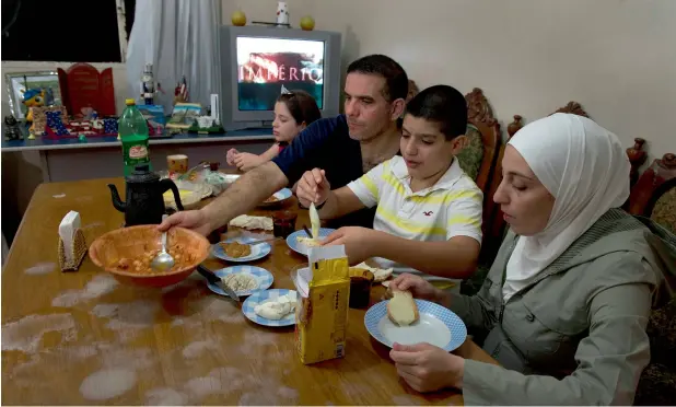  ?? — AFP ?? FEELS LIKE HOME: Syrian refugee Talal Al Tinawi has dinner with his wife Ghazal and their children Yara and Riad at home in Sao Paulo, Brazil. Brazil host over 1,700 Syrian refugees.