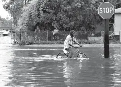  ?? Associated Press ?? A man tries to bike Sunday through the flooding from tropical storm Barry on LA Hwy 675 in New Iberia, La. Barry dumped rain as it slowly swept inland through Gulf Coast states Sunday.