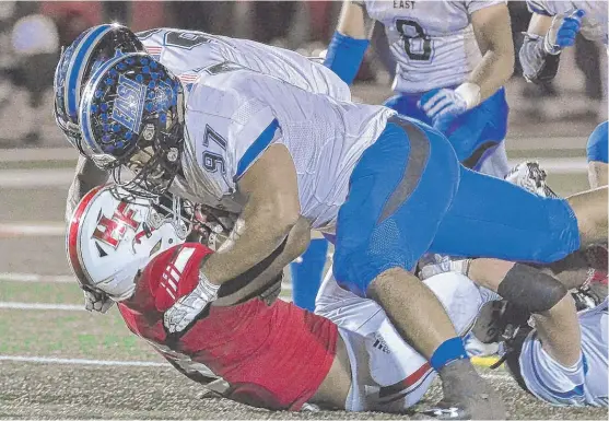  ?? | WORSOM ROBINSON/ FOR THE SUN- TIMES ?? Lincoln- Way East defensive lineman Jaden Hacha ( 97) helps to smother Homewood- Flossmoor running back Leon Tanna on Friday night.