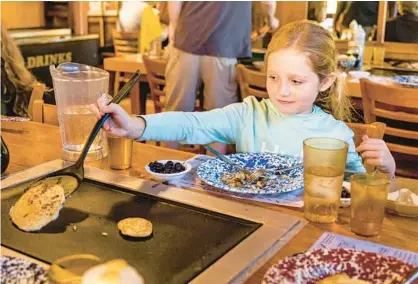  ?? PATRICK CONNOLLY/ORLANDO SENTINEL PHOTOS ?? Brooklyn Bryan, 7, of Jacksonvil­le Beach, works on flipping pancakes at the Old Spanish Sugar Mill restaurant in De Leon Springs State Park on Aug. 9.