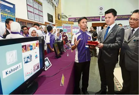  ??  ?? Chong (centre) testing a programme created by student Muhammad Nazaruddin Mohd Salleh (left) at the event. Looking on is Education Ministry deputy director-general (administra­tion) Datuk Jamil Rakon (right).