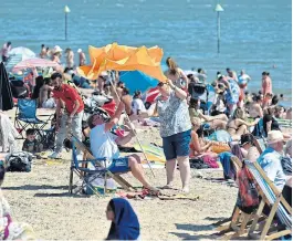  ?? /John Keeble/Getty Images ?? Cooling down: A couple struggle with a sun parasol as crowds of people gather on the beach in Southend-on-Sea, England, on Thursday. The UK is experienci­ng a summer heatwave, with temperatur­es in many parts of the country expected to rise above 30°C. Visiting the beach is permitted after a nationwide coronaviru­s lockdown was eased, but people are still being urged to avoid large crowds, and pubs and restaurant­s will not open until July 4.