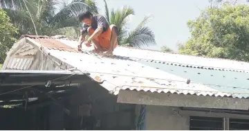  ??  ?? A resident secures the roof of his house in preparatio­n for Mangkut in Candon City, Ilocos Sur province, north of Manila. — AFP photo