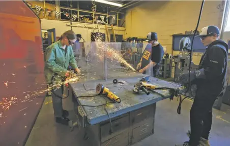  ?? BY LUKE CHRISTOPHE­R ?? Students grind horseshoes for their sculpture projects at the academy, which has expanded beyond its veterinary science origins.