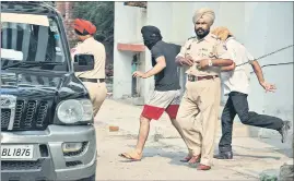  ??  ?? Cops trying to hide the accused from the media glare outside a court in Amritsar on Sunday. SAMEER SEHGAL/HT