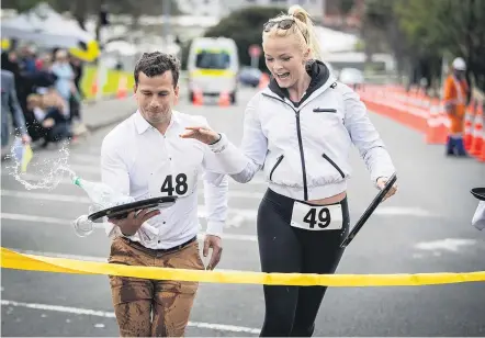  ?? Picture / Michael Craig ?? Act Party leader David Seymour is fouled on the line by Chrystal Chenery of Bachelor fame in The Parnell Waiters' Race celebrity event in Auckland last Sunday.