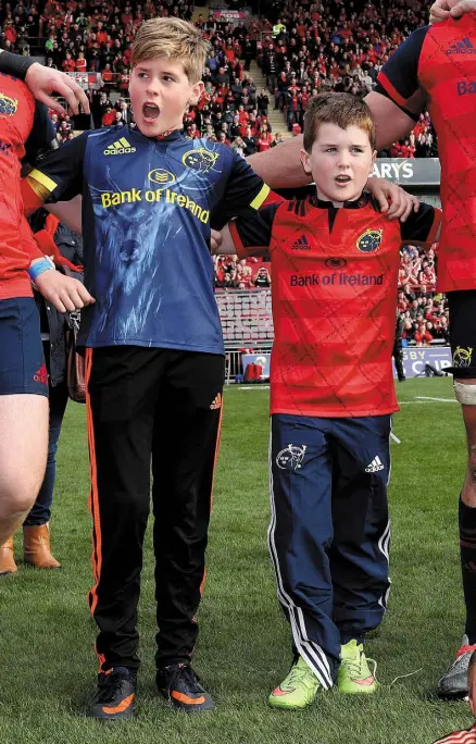  ??  ?? SUPPORTED: Tony and Dan Foley sing Stand Up And Fight with the Munster players, who formed a circle on the pitch with the boys after yesterday’s game to pay tribute to their dad Anthony, right Photo: Dan Sheridan/Inpho