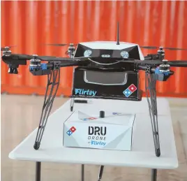  ?? NEWSCOM PHOTOS ?? TOPPING OUT: A delivery drone sits with a pizza box underneath before a test flight in Auckland, New Zealand, yesterday, as Domino’s plans to offer the world’s first commercial drone delivery service.