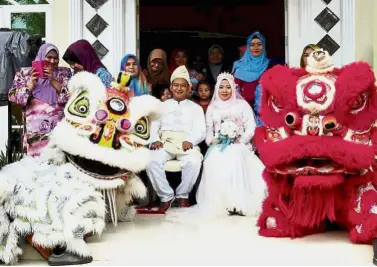  ??  ?? One for the album: The Shing Ann Associatio­n Lion Dance troupe posing with the bride and groom after performing at a Malay wedding ceremony in Pasir Pekan, Kelantan.