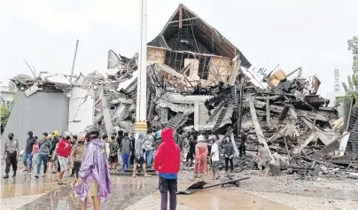  ?? PHOTO: ANTARA FOTO/AKBAR TADO VIA REUTERS ?? Rattled . . . People look at the damaged office of the governor of West Sulawesi following an earthquake in Mamuju, West Sulawesi province, Indonesia, yesterday.