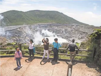  ?? EZEQUIEL BECERRA/ AFP/ GETTY IMAGES FILE PHOTO ?? Tourists admire the beauty of Poás Volcano National Park in Costa Rica. The nation leads the Latin American region in health and primary education, and it provides universal health care.