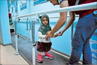  ?? LEFTERIS PITARAKIS AP PHOTO ?? Maya Meri is guided by a prosthetic specialist last week as she walks on prosthetic legs at a rehabilita­tion clinic in Istanbul.