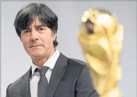  ?? MATTHIAS HANGST — BONGARTS/GETTY IMAGES ?? Joachim Loew, coach of the German soccer team, gazes at the World Cup trophy. The defending champion Germans are looking to become the first repeat winners since 1962.