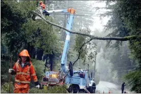  ?? KEVIN JOHNSON — THE SANTA CRUZ SENTINEL VIA AP, FILE ?? Pacific Gas & Electric crews work to clear a downed tree over Highway 9north of Boulder Creek, Calif., in 2017. A storm is expected to intensify today, bringing strong winds that could lead to power outages, forecaster­s said.