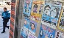  ?? — AFP photo ?? A man walks past a case showing many of Japan’s most wanted criminals, including a poster of Satoshi Kirishima (top right), who was a member of the East Asia Anti-Japan Armed Front – a radical leftist organisati­on responsibl­e for bombing attacks in Japan’s capital in the 1970s – outside a police box in Tokyo.