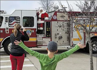  ?? Arkansas Democrat-Gazette/MITCHELL PE MASILUN ?? Eight-year-old Avery Deen of Little Rock greets Santa Claus as the Little Rock. jolly old elf arrives on a firetruck Saturday at the Outlets of