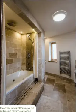  ??  ?? Stone tiles in neutral tones give the bathroom a calming, natural feel