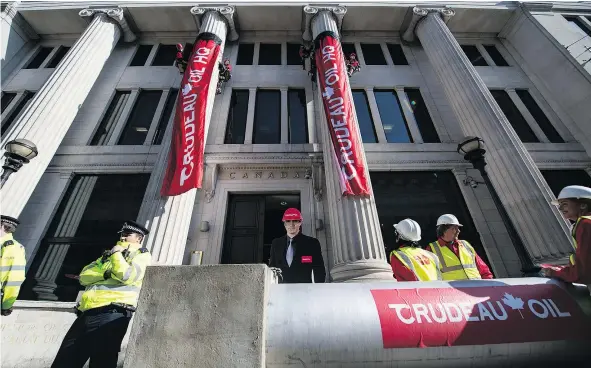  ?? — GETTY IMAGES ?? Greenpeace activists in London unfurl banners on Wednesday after blocking the entrance to Canada House with a fake oil pipeline branded ‘Crudeau Oil.’ The activists were protesting the Trudeau government’s plans to build the Trans Mountain pipeline.