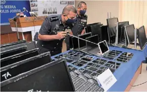 ?? ?? Seized goods: Comm ayob Khan (left) indicating one of the items at the Johor contingent police headquarte­rs that were confiscate­d. — bernama