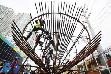  ?? AP ?? Filipino workers arrange metal rods at a government road project in suburban Quezon City.