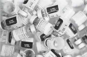  ?? JOHN LOCHER/AP ?? Empty vials of the Pfizer vaccine pile up Jan. 22 at a vaccinatio­n center in Las Vegas. Makers of COVID-19 vaccines need everything to go right as they scale up from early-stage production to hundreds of millions of doses.