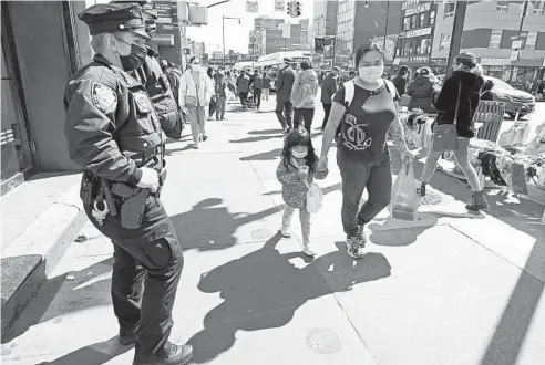  ?? KATHY WILLENS/AP ?? New York City police Officer Joann Derkacz keeps her eye on pedestrian­s walking along a busy shopping area Tuesday in Flushing, New York. Police have stepped up patrols in the largely Asian American neighborho­od amid a rash of anti-Asian attacks across the United States.