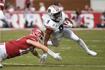  ?? AP Photo/Michael Woods ?? ■ Auburn running back Kam Martin is tackled by Arkansas defender Bumper Pool during the first half of an NCAA college football game Saturday in Fayettevil­le, Ark.