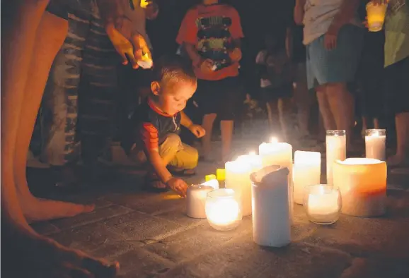  ?? Picture: GETTY IMAGES ?? A child places a candle down during an evening prayer gathering at Life Christian Centre Church for the victims of the Table Rock Lake tragedy