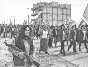  ?? MAURICIO LIMA/THE NEW YORK TIMES ?? Women, some of whom are waving the Rojava flag of Kurdish-controlled northern Syria, march on the outskirts of Kobani, during a protest on Feb. 10 against a Turkish military offensive in the country. Women wield significan­t authority in northern Syria...