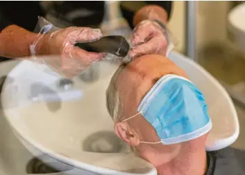  ?? Foto: Robert Michael/dpa ?? Haarewasch­en und das Tragen von Mund-Nase-Schutz gehört zu den Auflagen, unter denen Friseure momentan arbeiten dürfen.