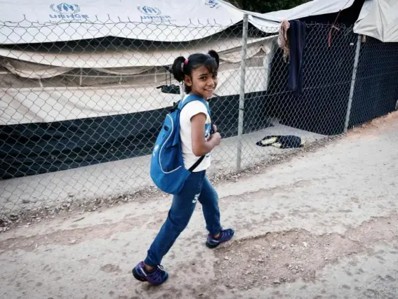  ?? (AFP/Getty) ?? Roza, a Syrian Kurd refugee, walks through a camp to reach a volunteer-run school