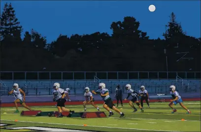  ?? RAY CHAVEZ — BAY AREA NEWS GROUP FILE ?? Members of Palo Alto High School football team practice as the full moon rises in the horizon in Palo Alto on Friday, Feb. 26.