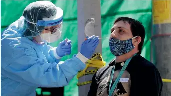  ?? AP ?? Tina Nguyen, left, a nurse at at the Internatio­nal Community Health Services clinic in Seattle’s Internatio­nal District, takes a nose swab sample from David Carroll, an ICHS employee, during walk and drive-up testing for Covid-19.