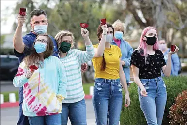  ?? PHOTOS BY ALEX HORVATH / THE CALIFORNIA­N ?? Pharmacy Director Jim Franckum with his wife, Janice, and children Janessa, Anna and Aspen rang bells during the Bakersfiel­d Heart Hospital COVID-19 Memorial on Thursday. The memorial honored frontline caregivers, patients and those who have been lost during the past year’s pandemic.