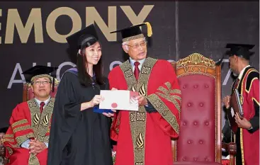  ??  ?? Ling receiving her scroll from Dr Abdul Rahman during the ceremony while Ng (seated) looks on.