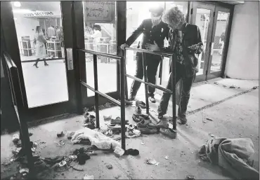  ?? (File Photo/AP/Brian Horton) ?? A security guard and an unidentifi­ed man look at an area where several people were killed Dec. 3, 1979, as they were caught in a surging crowd entering Cincinnati’s Riverfront Coliseum for a concert by the British rock band The Who.