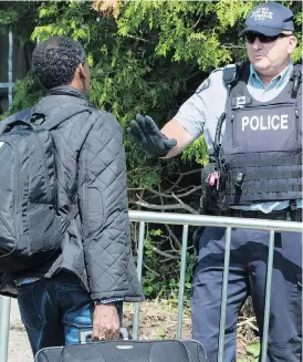  ?? THE CANADIAN PRESS/FILES ?? An RCMP officer stops an asylum seeker, who claims to be from Eritrea, as he crosses the border into Canada near Champlain, N.Y., south of Montreal.