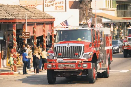  ?? Photos by Noah Berger / Associated Press ?? A fire truck, part of a procession carrying the body of firefighte­r Braden Varney, makes its way along Highway 140 in Mariposa.