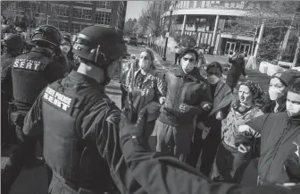  ?? ERIN CLARK VIA GETTY IMAGES ?? Police officers push back protesters who stood near barriers and watched as fellow demonstrat­ors were driven out in police vans on Saturday morning in Boston, the United States.