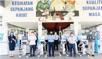  ??  ?? Lee (front row, centre), flanked by Morris on his left and Dr Wong, and others give the thumbs-up during the presentati­on of the ventilator­s to Miri Hospital.