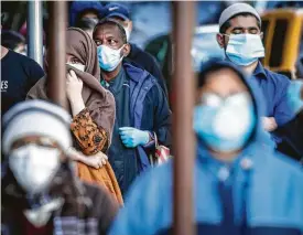  ?? John Minchillo / Associated Press ?? People wearing masks wait in line for food donations Wednesday in the Brooklyn borough of New York.