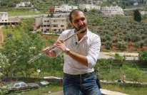  ??  ?? Ebaa Akroush, a 24-year-old Jordanian music graduate from the University of Jordan and first-prize winner of a culture ministry talent contest, plays the flute on his balcony in Fuheis town.