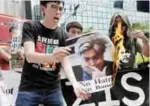  ?? —AFP ?? HONG KONG: Veteran activist and former Hong Kong lawmaker Leung Kwok-hung, centre right, and Avery Leung, centre left, chairman of the League of Social Democrats (LSD), burn a picture of former White House chief strategist Steve Bannon during a protest...