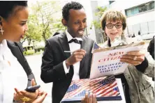  ??  ?? Mabire Osana (left) watches Brenda Berlin (right) help new U.S. citizen Tsegaye Keneni of Ethiopia register to vote.