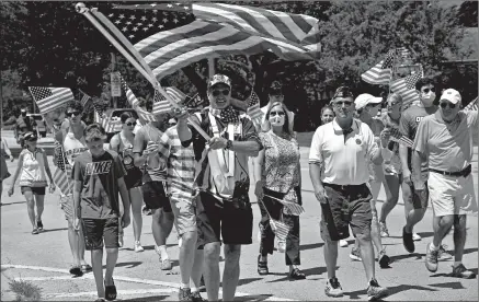  ?? JOE LEWNARD/AP ?? Veteran Matt Jaeger carries the American flag Saturday during an impromptu Fourth of July parade in Northbrook, Illinois.