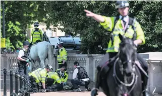  ?? Carl Court / Getty Images ?? A man is detained by police near Buckingham Palace in London on Wednesday, two days after a terrorist attack at a music concert in Manchester.