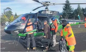  ??  ?? The stranded trampers are loaded into a rescue helicopter after their ordeal on Mt Tongariro. One woman almost died from hypothermi­a.