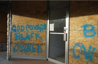  ??  ?? “Black owned” has been painted on a boarded-up storefront in Ferguson, Mo.