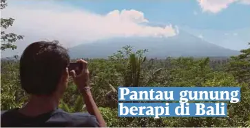  ??  ?? SEORANG penduduk merakam gambar Gunung Agung dari stesen pemantau di Kampung Rendang di Karangasem, Bali kelmarin. - Reuters